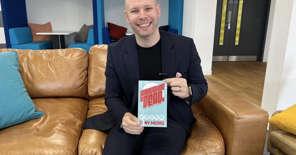 Tony Mears holding up his book, Innovation is Dead.